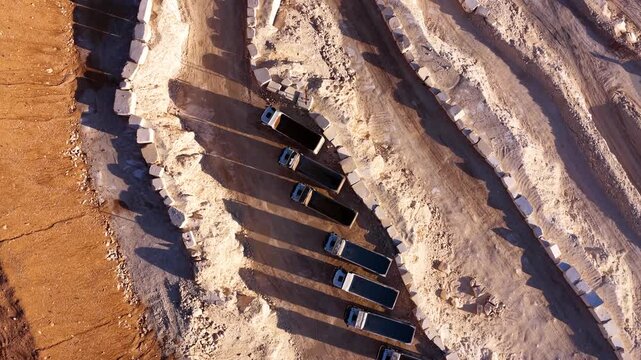 Aerial view of dump trucks lined up side by side at a marble quarry.