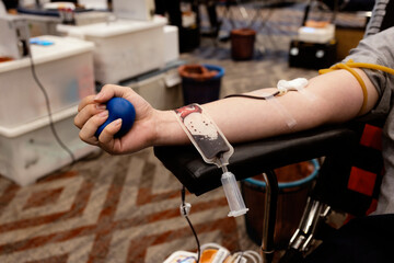 Blood Donation Process with Donor Holding Stress Ball and Blood Bag Collection in Hospital Setting