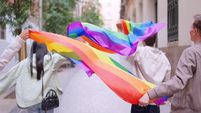 Back view of group of friends celebrating gay pride parade with a rainbow flag