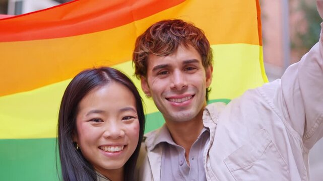 Happy young friends holding the rainbow flag