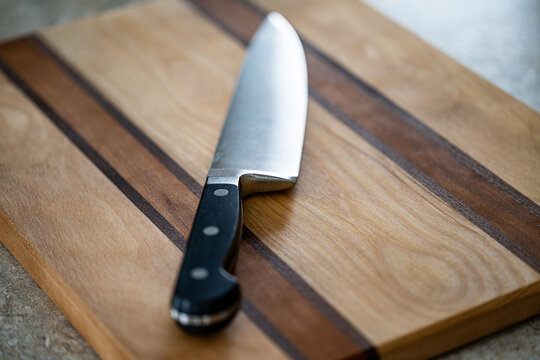 Chef Knife on Striped Wooden Cutting Board in Kitchen Setting