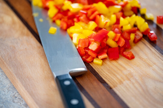 Diced Red and Yellow Bell Peppers with Chef Knife on Wooden Cutting Board