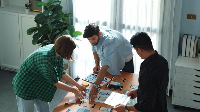 Top view of smart Ui designer brainstorming and planning about Ux Uo design or mobile interface wireframe design with diverse develop team. Caucasian programer walking and joining meeting.Convocation.