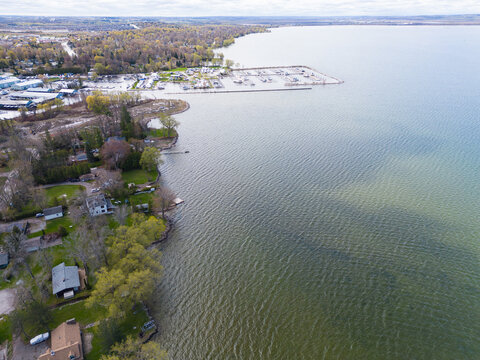 Aerial view capturing the shoreline of lake simcoe, featuring waterfront homes, a bustling yacht marina, and extensive green tree coverage in georgina, ontario, canada