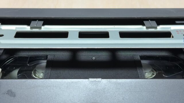 The VCR internal mechanism pulls the VHS tape into position for playback. This action creates a sequence of heavy mechanical clicks followed by a steady motorized whirring sound.