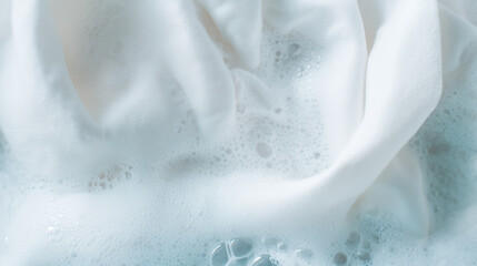 White clothes soaking in detergent water with foam bubbles, top view laundry cleaning concept true overhead flat lay composition, camera positioned directly above surface, 50mm mac