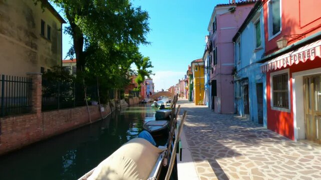 SLOW PAN SHOT - A view along Fondamenta di Terranova footpath in Burano. Colorful houses, school, Vigna and Terranova bridges and boats moored in the waterway.