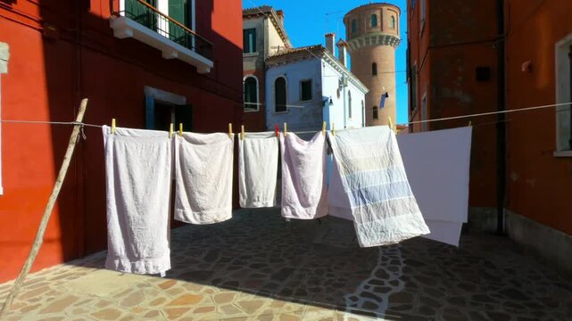 Burano street with laundry washed clothes hanging out to dry on ropes.