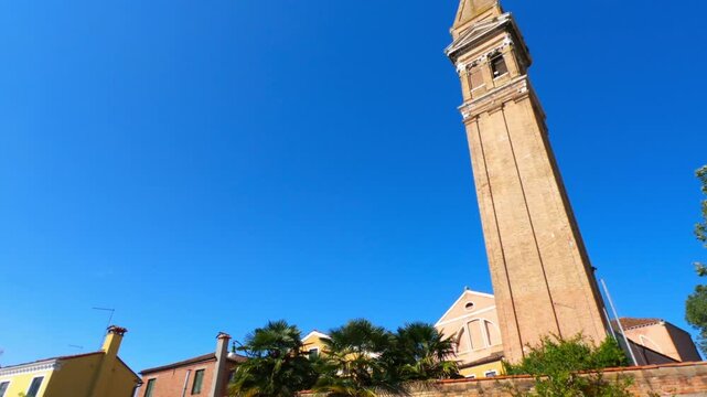 PAN SHOT - The leaning bell tower on the island of Burano in the Venice lagoon, Italy. Because of land subsidence it is inclined of 1.83 meters respect to its axis.