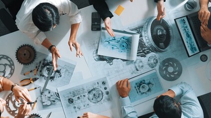 Top down aerial view of smart engineer team working together to design turbine engine. Professional technician discussing about jet engine construction while pointing at part of engine. Alimentation. © InfiniteFlow