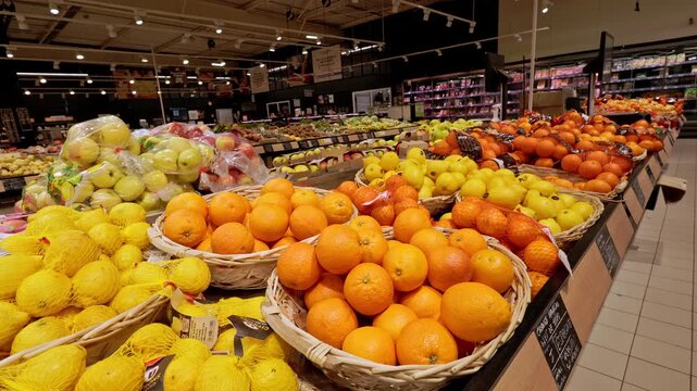 Dijon, France - February 21, 2026: Shelves of citrus fruits, oranges, and lemons at Super U grocery store. Empty supermarket interior with no people.