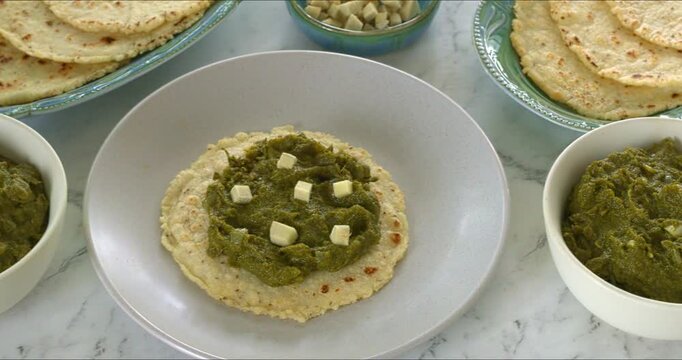 Mustard greens puree (sarson ka saag), cornmeal flatbreads (makki ki roti), and chopped ginger. Healthy, indian-style meal. Camera slide.