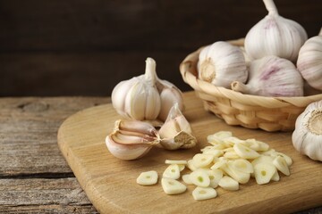 Cut garlic and bulbs on wooden table, closeup. Space for text