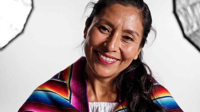 A smiling woman wearing a vibrant poncho in a modern setting, captured in a video showcasing her warm personality.