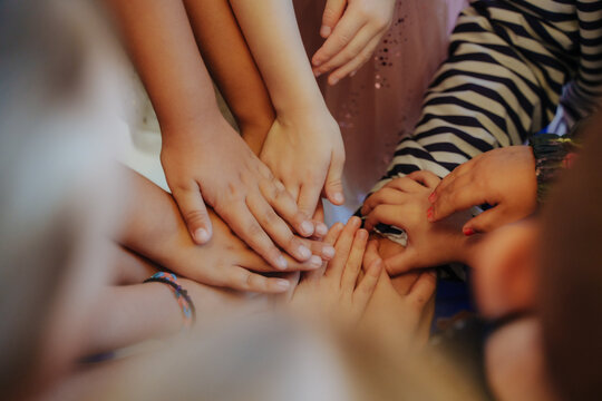 A group of teenagers holding hands, demonstrating unity and teamwork before the start of the game. Friends in nature with collaboration, community, or teaming up to create a team.