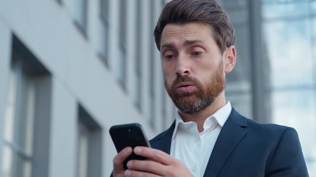 Upset Caucasian adult business in city sad with mobile phone mature businessman reading bad news in smartphone negative message dissatisfied frustrated male with online notification reject job failure