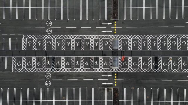 Overhead view ascending over newly laid car parking spaces in a supermarket car park with disabled parking bays, 