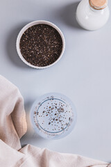 Obraz premium Refreshing coconut water drink with chia seeds in a glass on the table top and vertical view