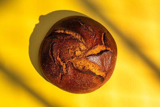 Round loaf of crusty bread on vibrant yellow backdrop