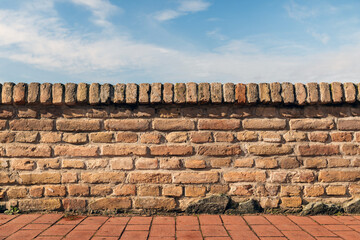 Old brick wall with terracotta coping and blue sky background