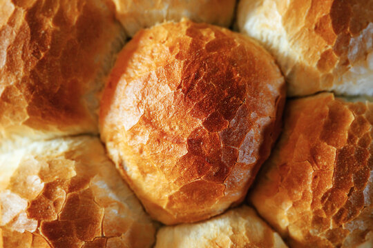 Close-up of golden baked bread rolls with crispy crust texture and warm natural light highlighting fresh bakery detail.