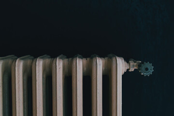 Vintage cast iron radiator with valve detail in dark room