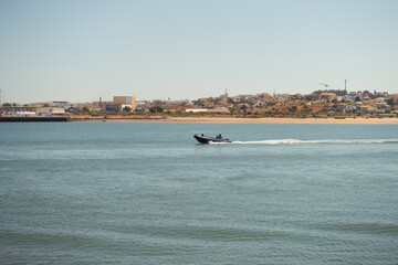 Obraz premium Semi-rigid boat or Zodiac sailing off the coast in the Portuguese Algarve. Recreational motorboat cruising on a sunny day.