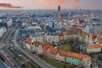 Obraz premium Aerial view of Wroclaw, Poland, shows St. Elizabeths Church tower, gabled townhouses, tram lined streets, and modern buildings in cool winter sunset light.