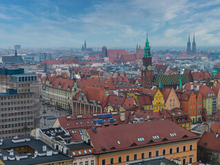 Fototapeta premium Aerial view of Wroclaw, Poland, shows Market Square, Gothic Old Town Hall with green clock tower, and Ostrow Tumski twin spires under soft daylight and slight haze.