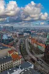 Obraz premium Daytime aerial view of Wroclaw, Poland, with red roof townhouses, modern offices, curving tram and road lines, church spire, and Wroclaw radio and TV mast after rain.