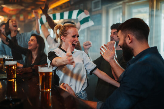 Sports fans celebrating goal cheering watching match in pub