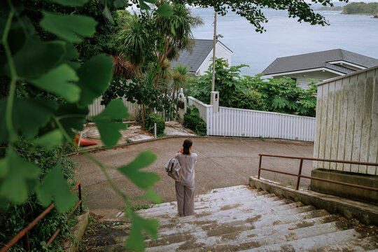 A woman experiencing seaside daily life in a coastal alleyway.
