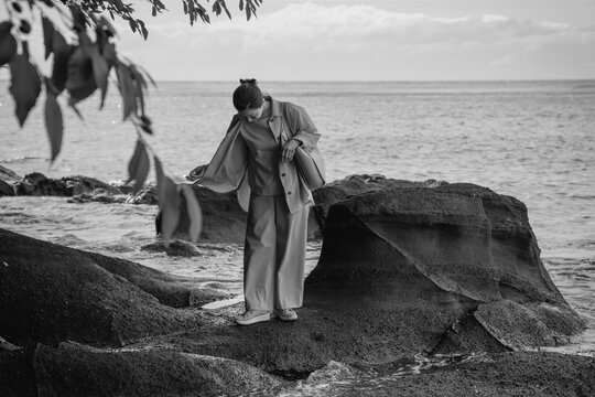 A woman exploring the sea's bounty among rocks.