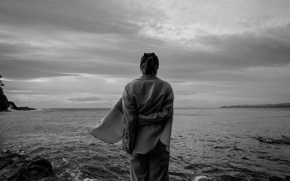 A woman bowing her head in thought in the sea breeze.