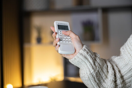 A person holding a remote control to adjust the air conditioning while working indoors.