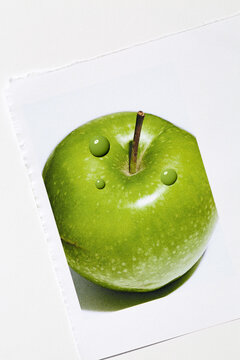 Fresh green apple with drops of green nail polish on the surface