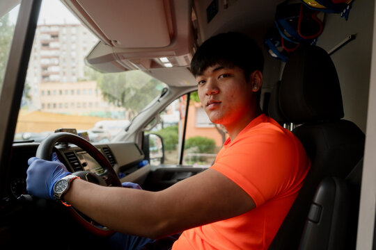 Paramedic driving ambulance wearing orange uniform