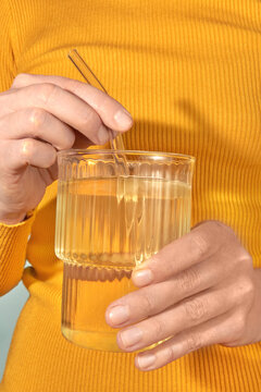 Anonymous mixing powder supplement in water, wearing yellow clothes.