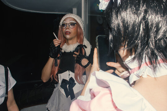 Drag performer in unique costume interacts at nighttime event