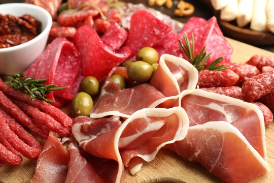 Charcuterie board with different cured meat, sausages and olives on table, closeup
