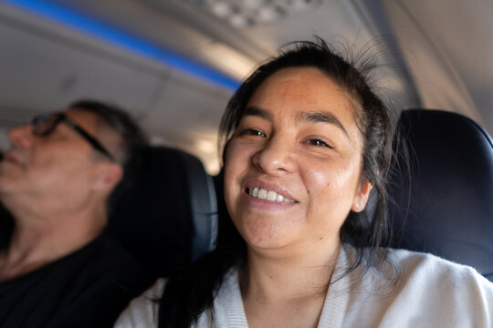 Smiling Woman Enjoying a Flight While Seated Next to a Man