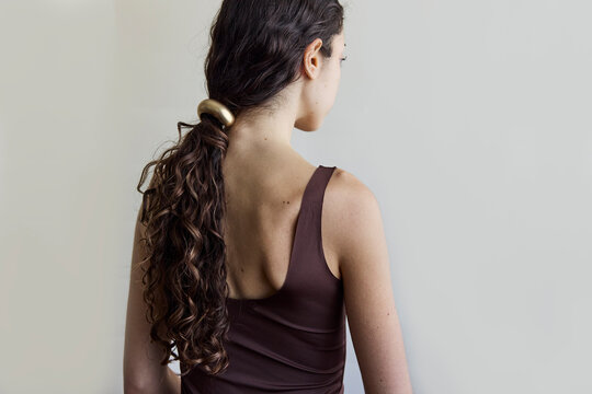 Woman looking away from camera with a low ponytail and gold hair cuff