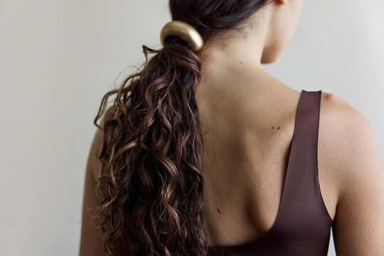 Woman looking away from camera with a low ponytail and gold hair cuff