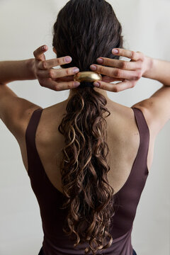 Woman looking away from camera with a low ponytail and gold hair cuff