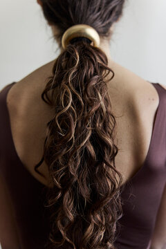 Woman looking away from camera with a low ponytail and gold hair cuff