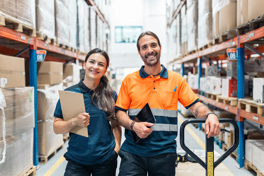 Warehouse workers smiling and holding tablet and clipboard