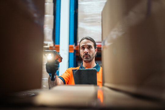 Logistic worker scanning packages with barcode reader in warehouse