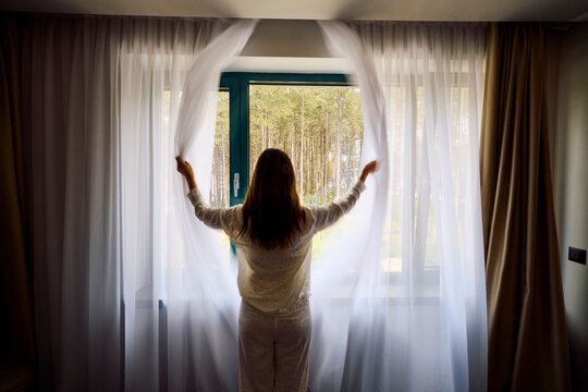 Woman opens the curtains
