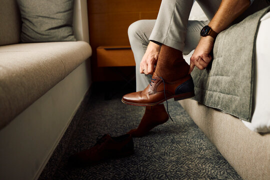 Man puts on his shoes in a hotel room
