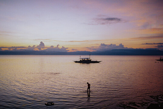 Man walking knee-high in water enjoying beach vacation at dusk 